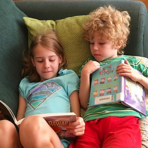 Two young children reading together side by side