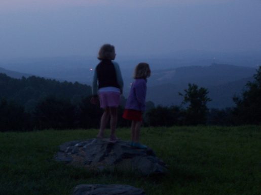 my two oldest girls, very young, silhouetted against a twilight sky and blue hills