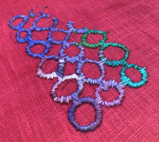 three in-progress rows of small irregular embroidered circles on red fabric