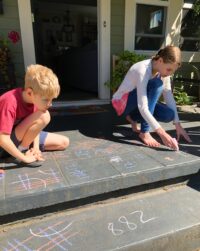 Huck and Rilla doing math with chalk on the front porch